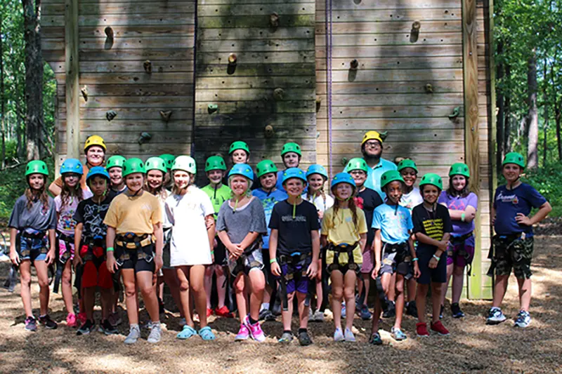 group with helmets on in front of the climbing wall