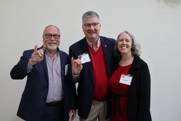 extension leadership smiling, making the wolfpack gesture